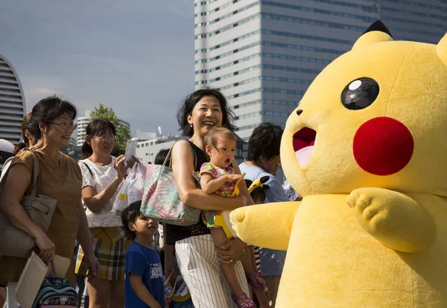People look at a performer dressed as Pikachu, a character from Pokemon series game titles, during the Pikachu Outbreak event hosted by The Pokemon Co. on August 9, 2017 in Yokohama, Kanagawa, Japan. (Photo by Tomohiro Ohsumi/Getty Images)