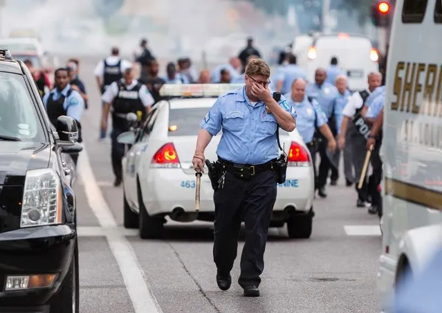 A policeman rubs his eyes after police attempted to disperse a crowd using what appeared to be teargas after a shooting incident in St. Louis, Missouri August 19, 2015. (Photo by Kenny Bahr/Reuters)
