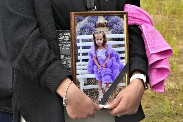 A woman carries a portrait of Liza, 4-year-old girl killed by Russian attack, during a funeral ceremony in Vinnytsia, Ukraine, Sunday, July 17, 2022. (Photo by Efrem Lukatsky/AP Photo)
