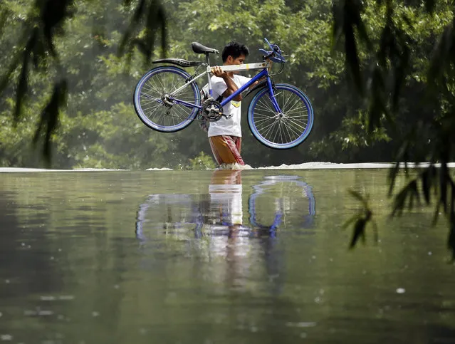 A Filipino villager carries a bicycle as he crosses a river in Las pinas city, south of Manila, Philippines, 09 July 2016. According to National Disaster Risk Reduction and Management Council (NDRRMC) executive director Ricardo Jalad, there were no immediate reports of any casualties, but the bad weather caused power interruptions, suspension of classes and work, parts of Luzon were flooded, and flights were grounded as Typhoon Nepartak exited the Philippine area of responsibility (PAR). Nepartak barreled through Taiwan packing winds of up to 191kph and gustiness of up to 234kph, the weather forecaster, Philippine Atmospheric Geophysical, and Astronomical Services Administration (PAGASA) said. (Photo by Francis R. Malasig/EPA)
