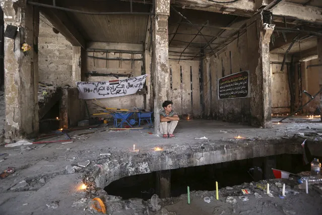 A man sits amid a makeshift memorial inside a burned mall at the scene of a massive truck bombing last Sunday that killed at least 186 people and was claimed by the Islamic State group, in the Karada neighborhood of Baghdad, Iraq, Sunday, July 10, 2016. (Photo by Hadi Mizban/AP Photo)