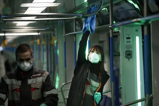 Moscow metro depot employees disinfect a metro train in Moscow, Russia, Monday, March 16, 2020. Starting from early March, Moscow authorities have been sending people who traveled to countries most affected by the coronavirus epidemic and returned with flu-like symptoms to a new hospital on the outskirts of the city. For most people, the new coronavirus causes only mild or moderate symptoms, such as fever and cough. For some, especially older adults and people with existing health problems, it can cause more severe illness, including pneumonia. (Photo by Pavel Golovkin/AP Photo)