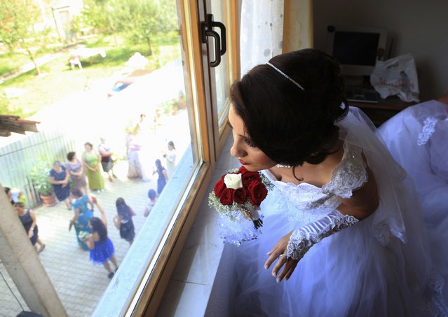 The bride Vlora Jonuzi waits for the groom's family to bring her to her new home, during their wedding in the village of Nerodime, southwest of the capital Prishtina August 9, 2014. In Kosovo, summer is a popular season to get married. (Photo by Hazir Reka/Reuters)