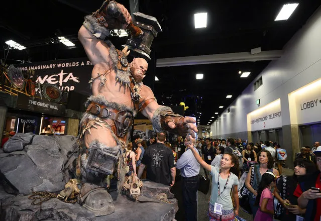 A fan reaches out to touch the finger of a giant "World of Warcraft" Orgrim statue in the exhibit hall on day two of Comic-Con International held at the San Diego Convention Center Friday, July 22, 2016, in San Diego.  (Photo by Denis Poroy/Invision/AP)