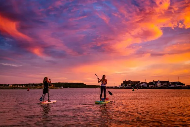 A couple paddleboarding as the sun sets over Mudeford, east of Christchurch, Dorset, England last night, on July 13, 2022. (Photo by Will Evans/Bournemouth News)