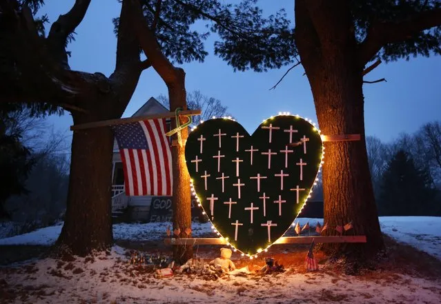 In this Saturday, December 14, 2013, file photo, a makeshift memorial with crosses for the victims of the Sandy Hook massacre stands outside a home in Newtown, Conn., the one-year anniversary of the shootings. (Photo by Robert F. Bukaty/AP Photo)