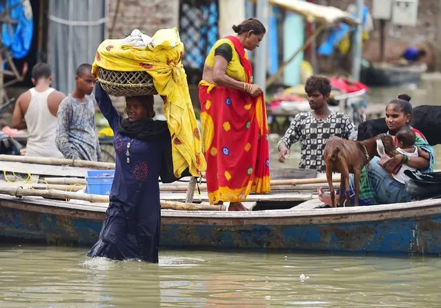 Flood-affected residents of a low lying area on the banks of the River Ganges move their belongings to drier ground at Daraganj area in Allahabad on August 19, 2022. (Photo by Sanjay Kanojia/AFP Photo)