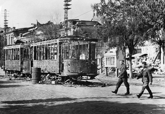 Nazi soldiers are seen here crossing a street in Vernolejinsk in the Southern Ukraine on September 3, 1941 after the Russians had evacuated it. Note the burnt-out street cars in the centre of the road fired by the Russians in accordance with their 'Scorched Earth' policy before they left. (Photo by AP Photo)