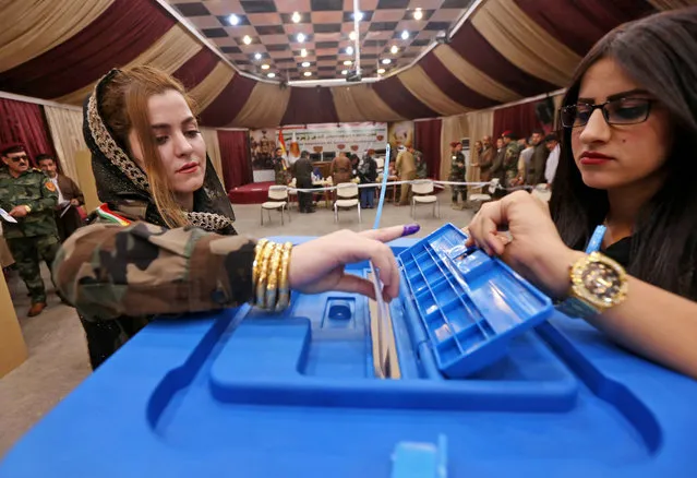 A female members of a Kurdish Peshmerga battalion casts her vote in the Kurdish independence referendum in Arbil, on September 25, 2017. Iraqi Kurds voted in an independence referendum in defiance of Baghdad which has warned of “measures” to defend Iraq' s unity and threatened to deprive their region of lifeline oil revenues. (Photo by Safin Hamed/AFP Photo)