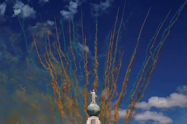 Coloured smoke trails are seen behind El Salvador del Mundo monument during the opening parade of the festivities of El Divino Salvador del Mundo (The Divine Savior of The World), patron saint of the capital city of San Salvador, El Salvador August 1, 2016. (Photo by Jose Cabezas/Reuters)