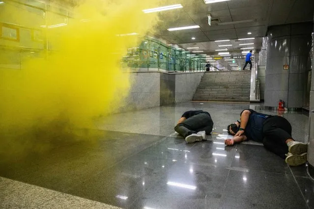 Participants lay down as smoke simulating a chemical agent is released during an anti-terror and anti-chemical drill on the sidelines of the joint South Korea-US Ulchi Freedom Shield (UFS) military exercises, at a metro station in Incheon, west of Seoul, on August 24, 2022. (Photo by Anthony Wallace/AFP Photo)