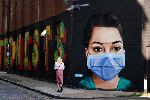 A woman walks past a mural depicting a nurse wearing a protective mask in Shoreditch, amid the coronavirus disease (COVID-19) outbreak, in London, Britain on April 21, 2020. (Photo by Henry Nicholls/Reuters)