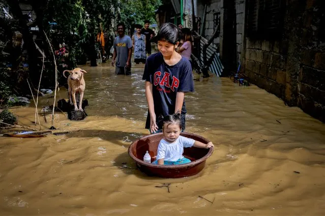 A woman pushes a child aboard a plastic basin as they wade through floodwaters brought about by Super Typhoon Noru on September 26, 2022 in San Miguel, Bulacan province, Philippines. Super Typhoon Noru made landfall in the Philippines overnight, causing widespread flooding and leaving at least five dead. High winds and heavy rains have flattened villages and have increased the threat of landslides. (Photo by Ezra Acayan/Getty Images)