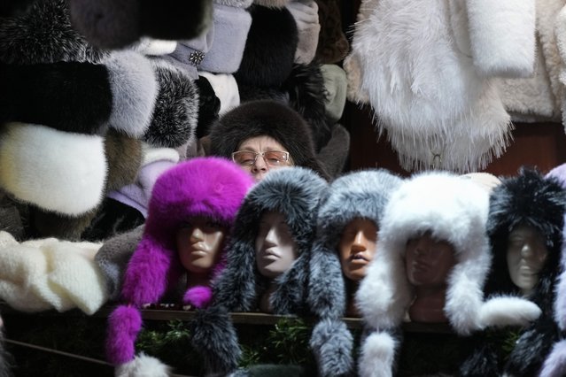 A woman sells winter hats at a Christmas fair opened prior to incoming Christmas and New Year festivities in St. Petersburg, Russia, Friday, December 20, 2024. (Photo by Dmitri Lovetsky/AP Photo)