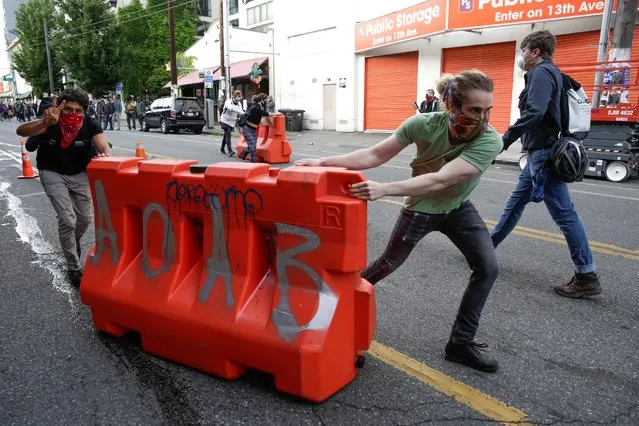 Protesters move barricades outside the Seattle Police Department's East Precinct after the building was boarded up and vacated as people rally against racial inequality and the death in Minneapolis police custody of George Floyd, in Seattle, Washington, U.S. June 8, 2020. (Photo by Jason Redmond/Reuters)