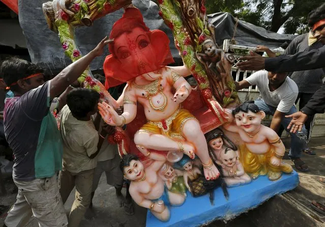 Devotees prepare to carry an idol of the Hindu god Ganesh, the deity of prosperity, to a place of worship on the first day of the ten-day-long Ganesh Chaturthi festival in Ahmedabad, India, September 17, 2015. During the festival, the idols will be taken through the streets in a procession accompanied by dancing and singing, and will be immersed in a river or the sea in accordance with the Hindu faith. (Photo by Amit Dave/Reuters)