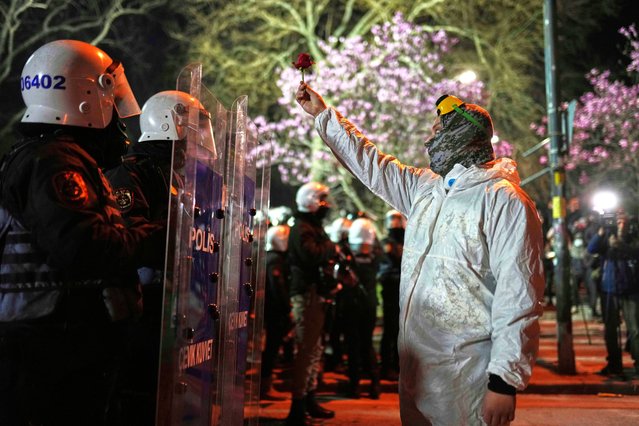 A protesters holds up a flower as stands in front of riot police officers during a protest against the arrest of Istanbul's Mayor Ekrem Imamoglu, in Istanbul, Turkey, Saturday, March 22, 2025. (Photo by Francisco Seco/AP Photo)