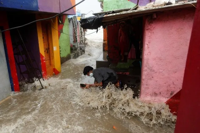 A boy records a video on his phone as water enters a slum area during high tide in Mumbai, India, July 6, 2020. (Photo by Francis Mascarenhas/Reuters)