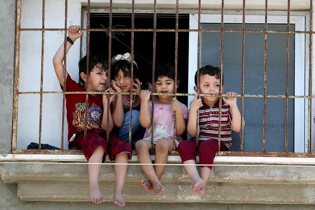 Children watch a rally through a home window fence as Palestinians call for a “day of rage” to protest against Israel's plan to annex parts of the Israeli-occupied West Bank, in Gaza City on July 1, 2020. (Photo by Mohammed Salem/Reuters)