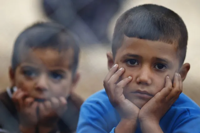 Kurdish refugee children from the Syrian town of Kobani sit behind a fence in a camp in the southeastern town of Suruc on the Turkish-Syrian border, October 19, 2014. (Photo by Kai Pfaffenbach/Reuters)