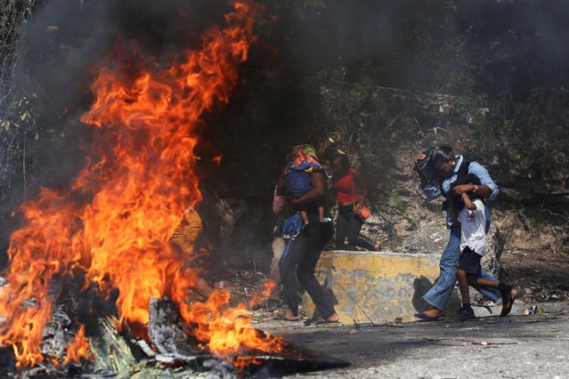 People walk past a burning barricade during a demonstration against insecurity, in Port-au-Prince, Haiti, on March 19, 2025. (Photo by Jean Feguens Regala/Reuters)