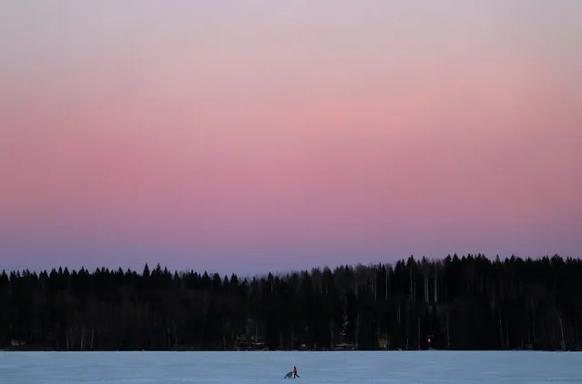 A woman pushes a pram as she walks over a frozen lake during sun down at the Pajulahti sports center near Lahti, Finland, February 21, 2017. (Photo by Kai Pfaffenbach/Reuters)