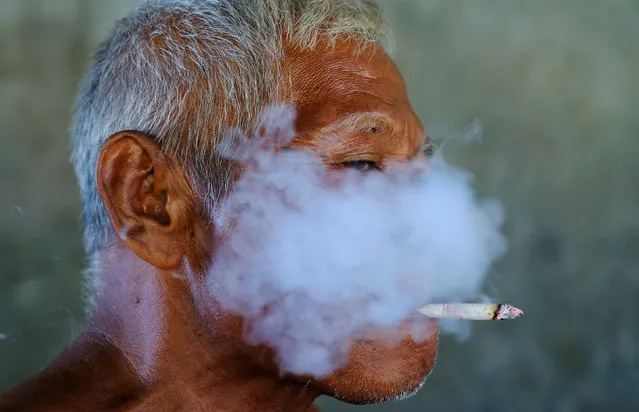 A worker smokes a cigarette during a break at a fabric factory in Solo, Indonesia Central Java province, August 11, 2016. (Photo by Reuters/Beawiharta)