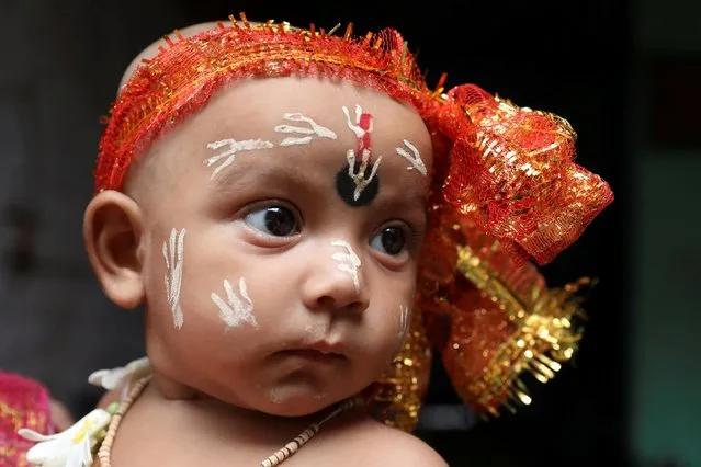 A child dressed as Hindu Lord Krishna accompanies his family for prayers during Janmashtami, or the birth anniversary of Lord Krishna, at a temple, in Kolkata, India, August 11, 2020. (Photo by Rupak De Chowdhuri/Reuters)