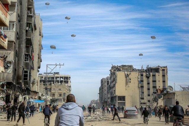 Palestinians run along a street as humanitarian aid is airdropped in Gaza City on March 1, 2024, amid the ongoing conflict between Israel and the Hamas militant group. For months, aid workers have warned of an increasingly desperate situation for Gazan civilians, and on February 26 an official from the UN humanitarian office OCHA said widespread starvation was “almost inevitable”. (Photo by AFP Photo)