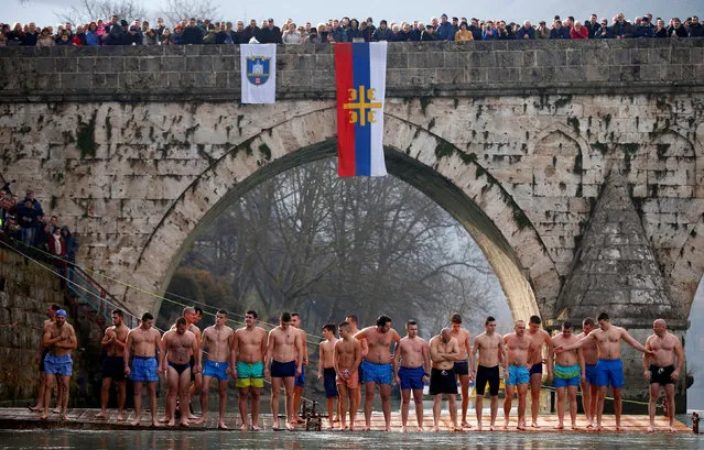 Men wait before a swim to try retrieve a cross from the water during Epiphany Day celebrations in Visegrad, Bosnia and Herzegovina, January 19, 2018. (Photo by Dado Ruvic/Reuters)