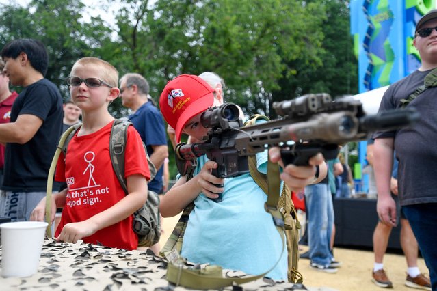 A child is allowed to inspect military hardware at one of the many booths set up on the National Mall during the Army 250th Anniversary Parade at the National Mall in Washington, DC on June 14, 2025. Trump's long-held dream of a parade will come true as nearly 7,000 troops plus dozens of tanks and helicopters rumble through the capital in an event officially marking the 250th anniversary of the US army. (Photo by Matthew Hatcher/AFP Photo)