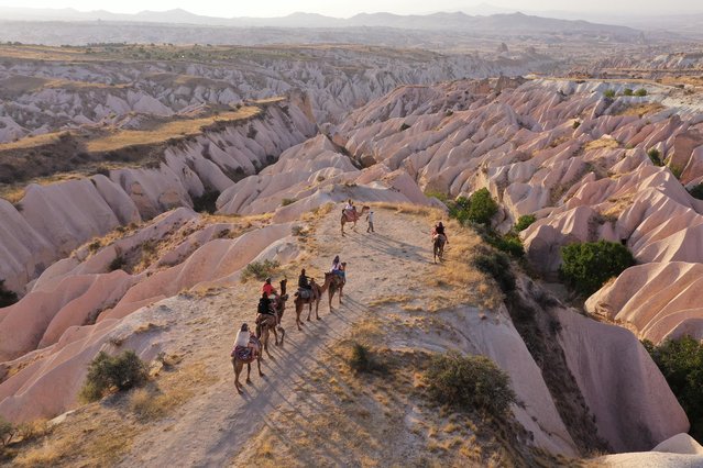 An aerial view of tourists riding camels while touring the fairy chimneys at the historical Cappadocia region, located in Central Anatolia's Nevsehir province, Turkey on September 13, 2020. Cappadocia is preserved as a UNESCO World Heritage site and is famous for its chimney rocks, hot air balloon trips, underground cities and boutique hotels carved into rocks. In Turkey's one of the most important tourism regions Cappadocia, local and foreign tourists get the chance of enjoying the scenery participating air balloon tours in the early hours of the morning. In the last five years, Among the 13 million 91 thousand 614 tourists who visited the museums and ruins in the region, 2 million 201 thousand 284 tourists participated in the hot air balloon tour and watched natural beauties from the sky. (Photo by Behcet Alkan/Anadolu Agency via Getty Images)