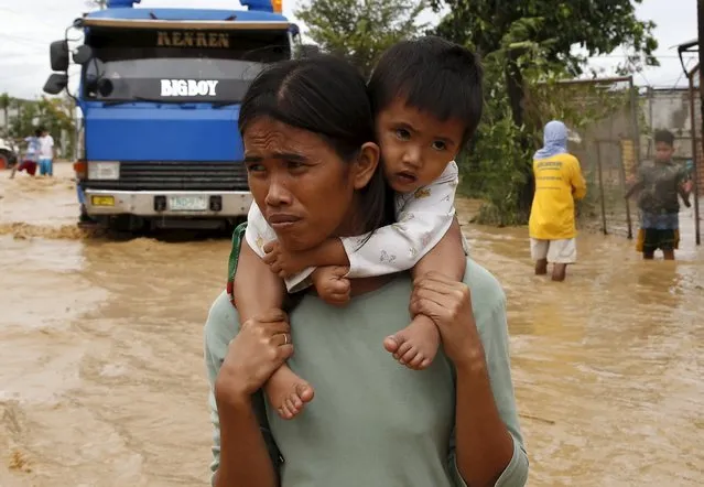 A woman carries her baby on her shoulder as they wade along a flooded highway in Sta Rosa, Nueva Ecija in northern Philippines October 19, 2015, after it was hit by Typhoon Koppu. (Photo by Erik De Castro/Reuters)