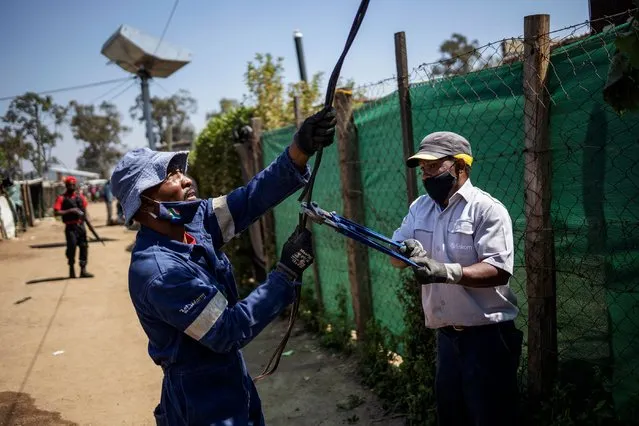 Eskom employees dismantle an illegal electricity substation during an operation conducted by South African electricity public utility Eskom to remove illegal connections in Diepsloot, Johannesburg, on September 29, 2020. (Photo by Michele Spatari/AFP Photo)