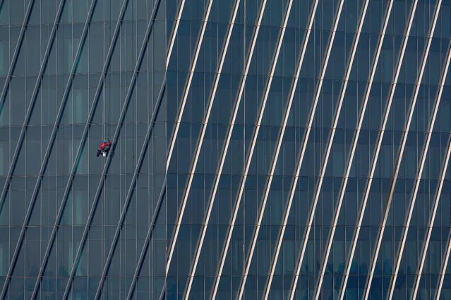 A man hangs from a rope as he cleans the windows of an office building in Bangkok, Thailand on February 2, 2023. (Photo by Athit Perawongmetha/Reuters)