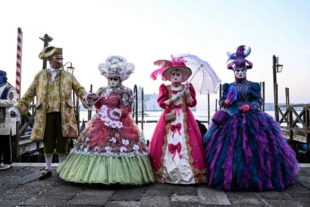 Masked revellers wearing traditional carnival costumes pose during the carnival in Venice on February 12, 2023. (Photo by Miguel Medina/AFP Photo)