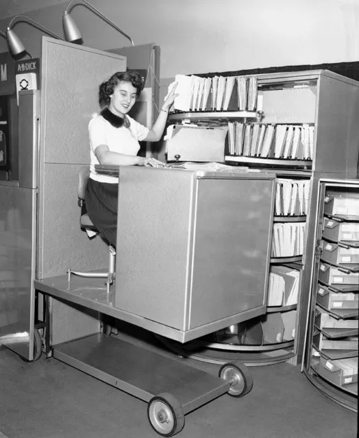 Jane Martin remains seated and “gets her filing done” using the “Corresfile” electric/hydraulic lift and circular file system at the Office and Management Association's 11th Annual Seminar and Business Show in Chicago, Ill., March 6, 1953. The electrically operated hydraulic lift raises a person from floor level to five feet alongside a circular file. The circular file has six shelves and each holds the equivalent of three file drawers. The Corresfile is an innovation of the Wassell Organization of  Westport, Conn. (Photo by Edward Kitch/AP Photo)