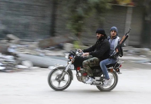 Rebel fighters ride a motorbike in the old city of Aleppo December 7, 2014. Picture taken December 7, 2014. (Photo by Abdalrhman Ismail/Reuters)