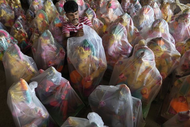 A worker covers an idol of elephant headed Hindu god Ganesha prepared for sale for the upcoming Ganesh Chaturthi festival, in Jammu, India, Friday, August 22, 2025. (Photo by Channi Anand/AP Photo)