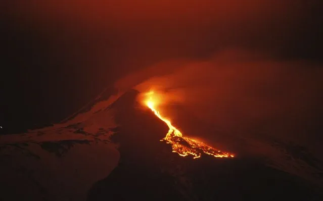In this photo, lava flows during an eruption of the snow capped Mount Etna volcano, near the Sicilian town of Catania, southern Italy. (Photo by Davide Caudullo/AP Photo/LaPresse)