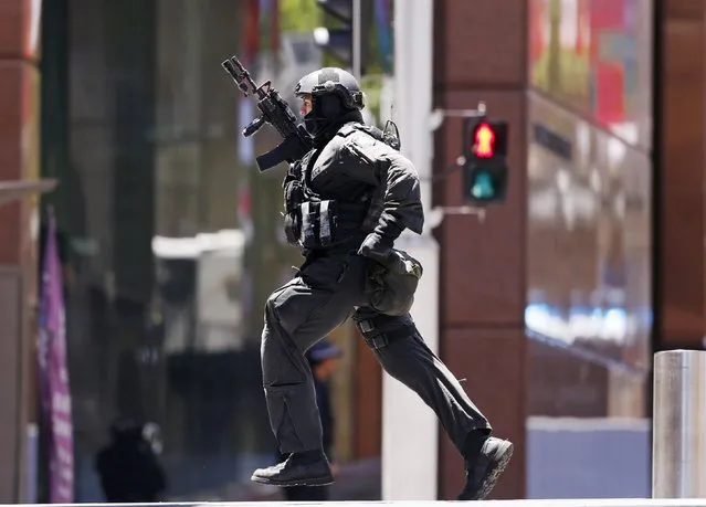 A police officer runs across Martin Place near Lindt cafe, where hostages are being held, in central Sydney December 15, 2014. Hostages were being held inside the central Sydney cafe where a black flag with white Arabic writing could be seen in the window, local television showed on Monday, raising fears of an attack linked to Islamic militants. (Photo by David Gray/Reuters)