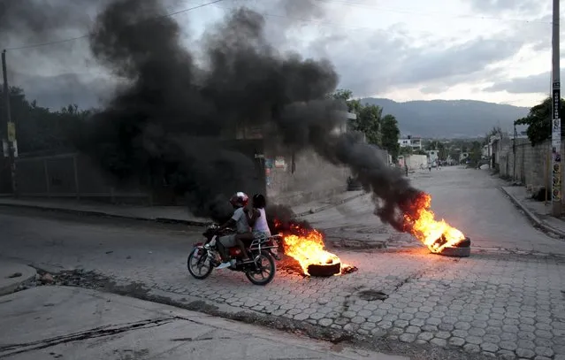 A motorbike passes burning tyres at a barricade during protests after the announcement of the results of the presidential election, on a street in Port-au-Prince, Haiti, November 5, 2015. Ruling party candidate Jovenel Moise led voting in Haiti's Oct. 25 presidential election with 32 percent, followed by former government executive Jude Celestin with 25 percent, according to official results announced on Thursday. (Photo by Andres Martinez Casares/Reuters)