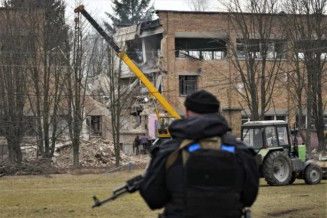 A police officer stands guard at the scene of a drone attack in the town of Rzhyshchiv, Kyiv region, Ukraine, Wednesday, March 22, 2023. (Photo by Efrem Lukatsky/AP Photo)