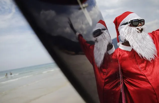 Carlos Bahia, dressed as Santa Claus, waves to people at the Maresias beach, in the state of Sao Paulo December 9, 2014. (Photo by Nacho Doce/Reuters)