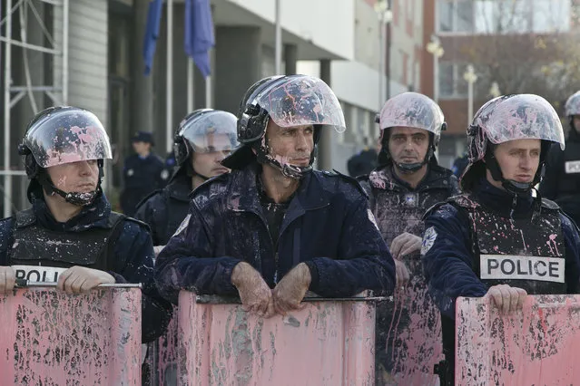 Kosovo police in riot gear are seen covered in pink paint after clashes outside Kosovo parliament building in the capital Pristina on Tuesday, November 17, 2015. (Photo by Visar Kryeziu/AP Photo)