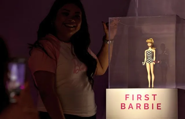 A woman poses for a picture next to a Barbie doll as she visits the World of Barbie immersive experience preview in Santa Monica, California, U.S., April 12, 2023. (Photo by Mario Anzuoni/Reuters)