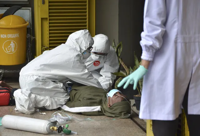 Paramedics wearing protective suits amid fears of coronavirus outbreak check on a man who collapsed outside a clinic in Jakarta, Indonesia, Thursday, March 26, 2020. It's not immediately clear what caused the man to collapse. The U.S. Embassy in Indonesia has ordered the departure of employees' family members under the age of 21 from its missions in the country where new COVID-19 patients have surged in the past week with high fatality. (Photo by Muchlis Akbar/AP Photo)