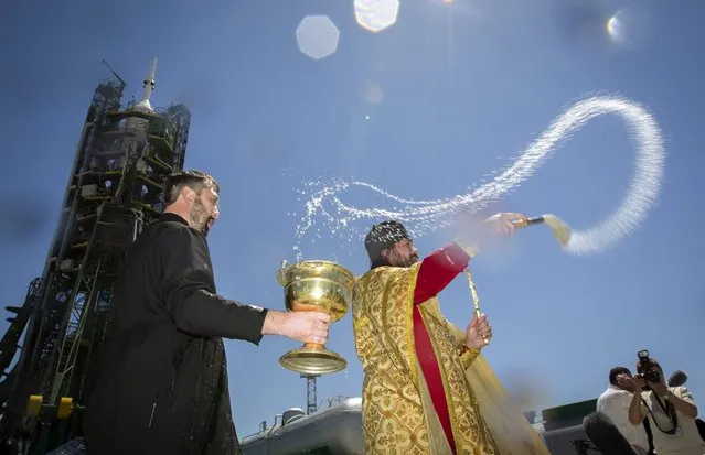An Orthodox priest (C) conducts a blessing service in front of the Soyuz TMA-09M spacecraft on the launch pad at Baikonur cosmodrome May 27, 2013. Soyuz with U.S. astronaut Karen Nyber, Italian astronaut Luca Parmitano and Russian cosmonaut Fyodor Yurchikhin is due to travel to the International Space Station on May 29. (Photo by Shamil Zhumatov/Reuters)