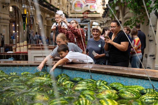 Children reach out for watermelons in a fountain at the start of the watermelon season in the center of the GUM, Moscow's largest luxury goods store at Red Square, in Moscow, Russia, Tuesday, August 6, 2024. (Photo by Alexander Zemlianichenko/AP Photo)