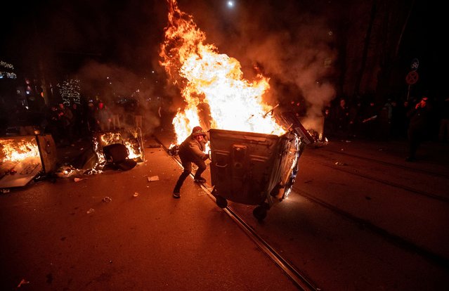 A protester pushes a burning garbage bin during scuffles with police at a demonstration organised by Bulgaria's opposition PP-DB coalition against the proposed financial framework of the country's budget, Sofia, Bulgaria, on December 1, 2025. (Photo by Dimitar Kyosemarliev/Reuters)